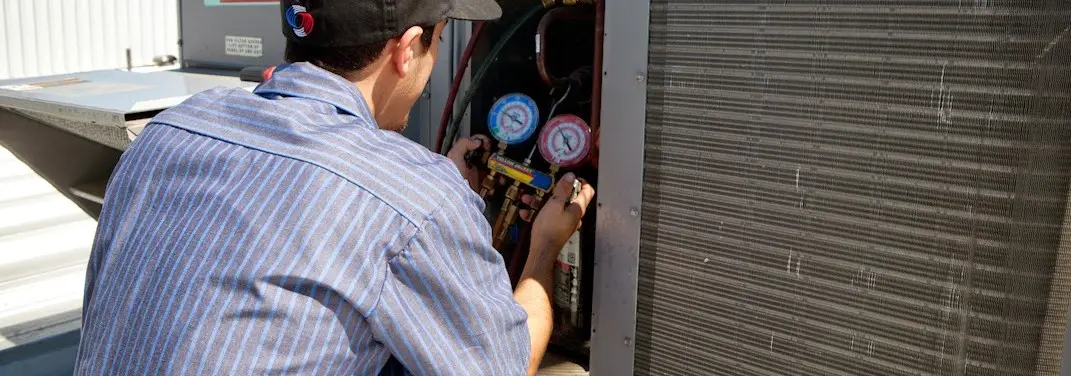 HVAC technician servicing a condenser unit in Dixon